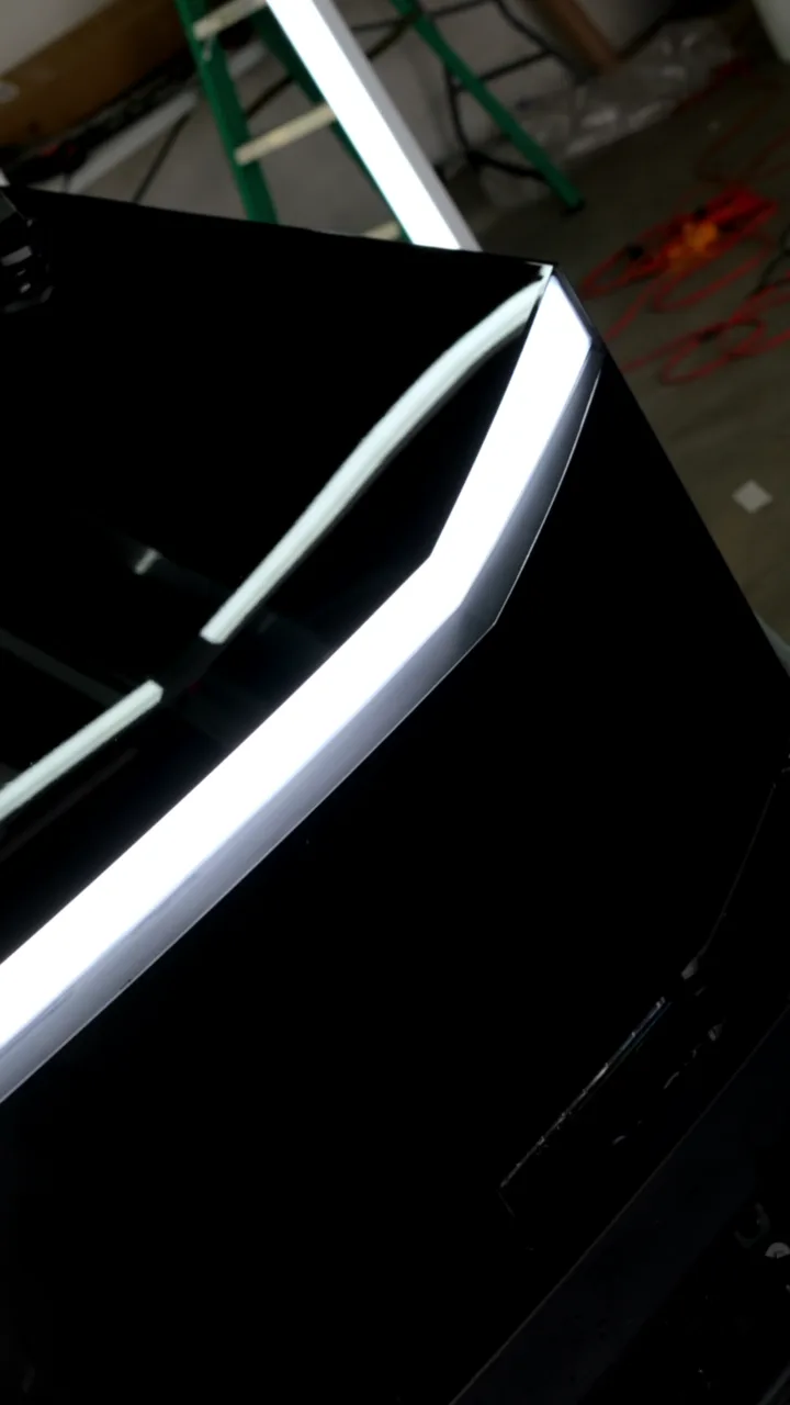Light bar edge of a gloss black Cybertruck under shop lights